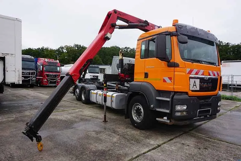Orangefarbener MAN Lkw mit ausgefahrenem Ladekran